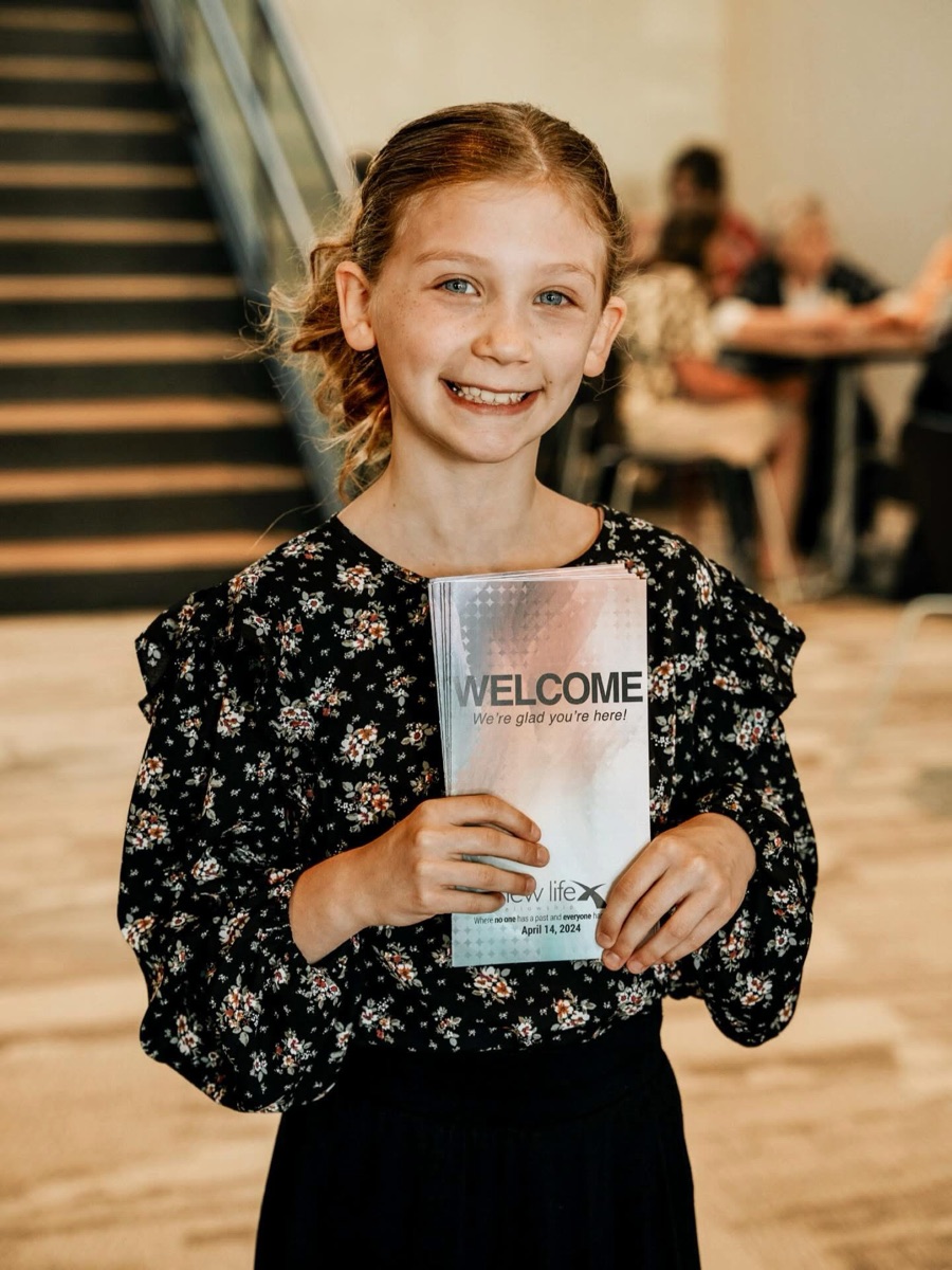 A girl holding a New Life welcome card
