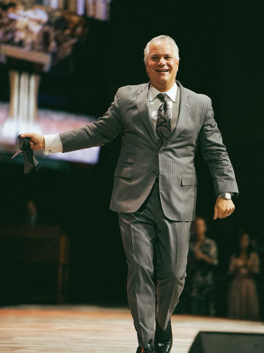 Pastor Harpole crossing the platform mid-service, smiling