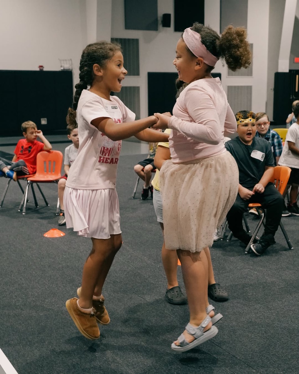 Two girls holding hands and dancing at a church family night